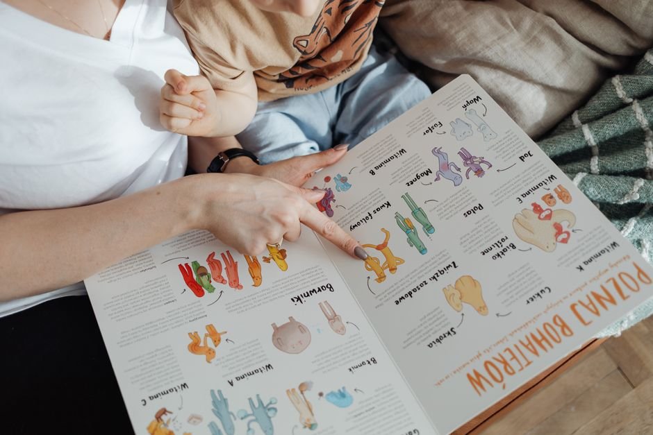 A parent and toddler reading a picture book together on a sofa