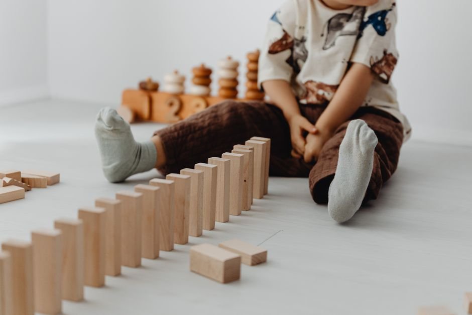 A quiet toddler playing alone with wooden toys
